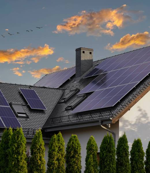 Modern house with blue solar panels on the roof. End of the day, sunset. Idyllic atmosphere. Large modern house with solar panels on a pitched roof. Natural light at sunset. Blue solar panels.